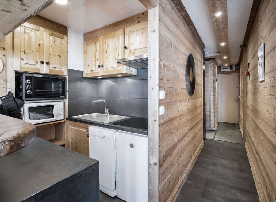 This chalet-style kitchen features wooden cabinetry, a compact sink, and modern appliances, maximizing space efficiency.