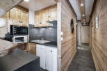 This chalet-style kitchen features wooden cabinetry, a compact sink, and modern appliances, maximizing space efficiency.