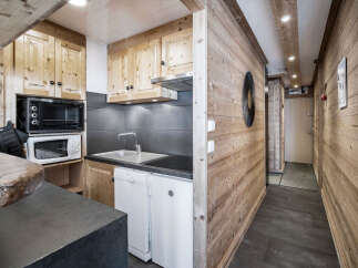 This chalet-style kitchen features wooden cabinetry, a compact sink, and modern appliances, maximizing space efficiency.