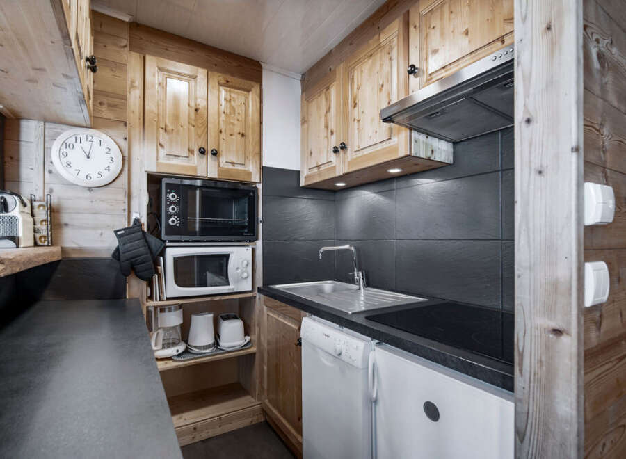 This charming kitchen features wooden cabinetry, a sleek black countertop, and modern appliances.