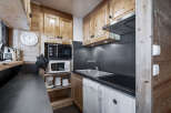 This charming kitchen features wooden cabinetry, a sleek black countertop, and modern appliances.