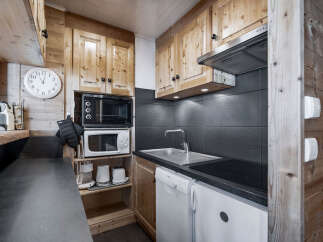 This charming kitchen features wooden cabinetry, a sleek black countertop, and modern appliances.