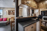 This charming property features a cozy living area with wood-paneled walls, seamlessly connected to a compact yet functional kitchen.