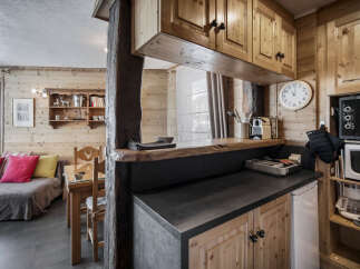 This charming property features a cozy living area with wood-paneled walls, seamlessly connected to a compact yet functional kitchen.