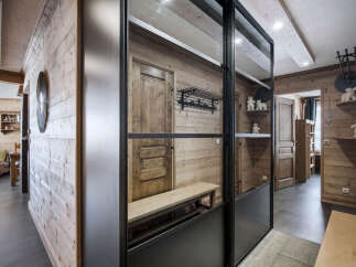 Discover a cozy chalet featuring natural wood walls, a stylish metal and glass partition, and unique decor elements.