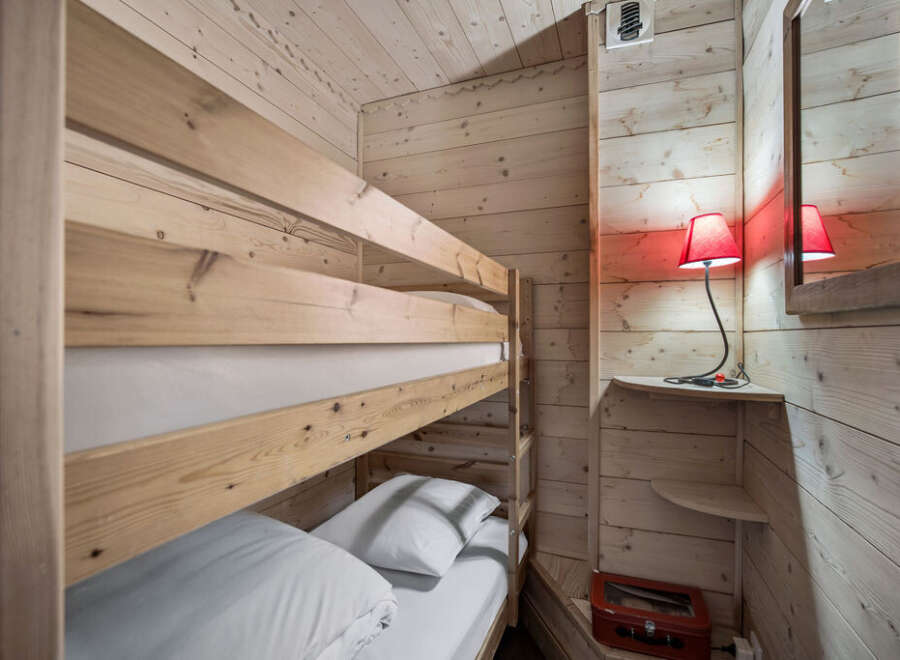 This cozy bunk room features a wooden bunk bed with crisp white linens, perfect for a vacation rental or family home.