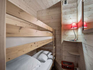 This cozy bunk room features a wooden bunk bed with crisp white linens, perfect for a vacation rental or family home.