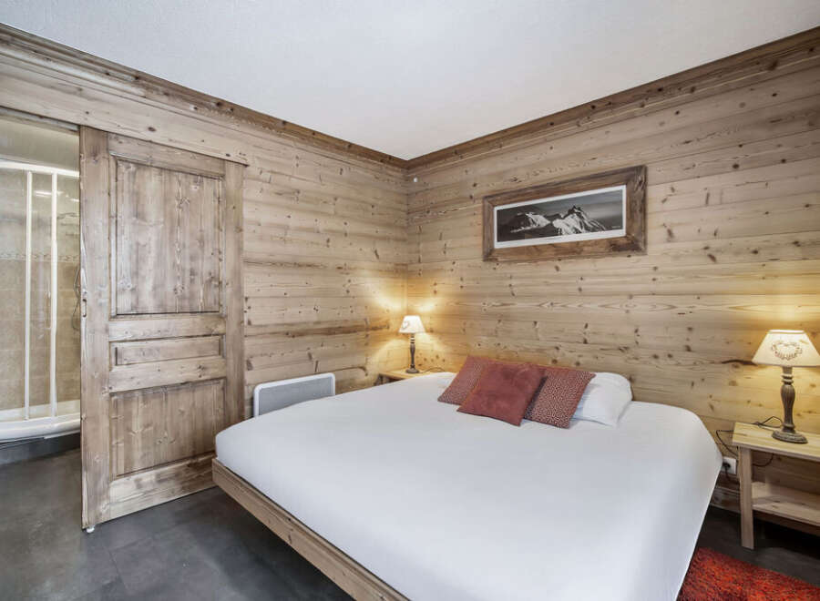 This inviting bedroom features warm wood paneling, creating a cozy, chalet-style atmosphere.