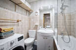 This bathroom features beige tile walls, a white vanity with marble countertop, and a shower-tub combo.