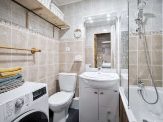 This bathroom features beige tile walls, a white vanity with marble countertop, and a shower-tub combo.