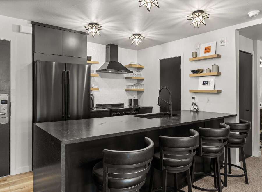 This modern kitchen features sleek black cabinetry, stainless steel appliances, and stylish star-shaped lighting fixtures.