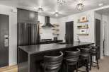 This modern kitchen features sleek black cabinetry, stainless steel appliances, and stylish star-shaped lighting fixtures.