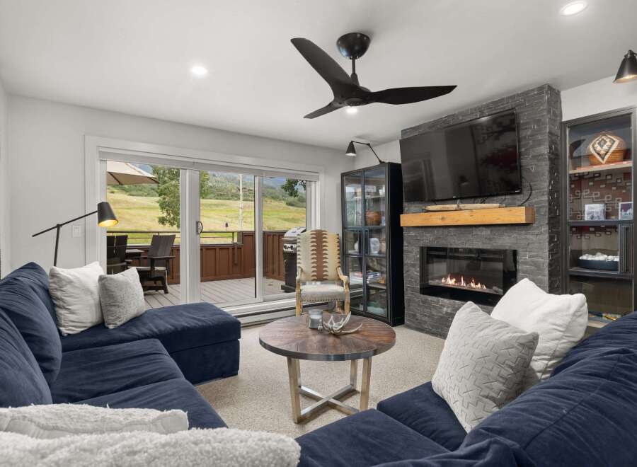 This inviting living room boasts a cozy fireplace with a stone surround, perfect for relaxing evenings.