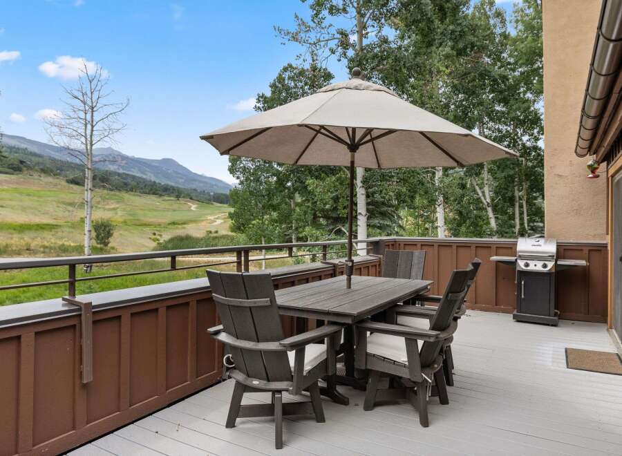 Enjoy outdoor dining with a view from this property's deck, complete with a dining table, chairs, and umbrella for shade.