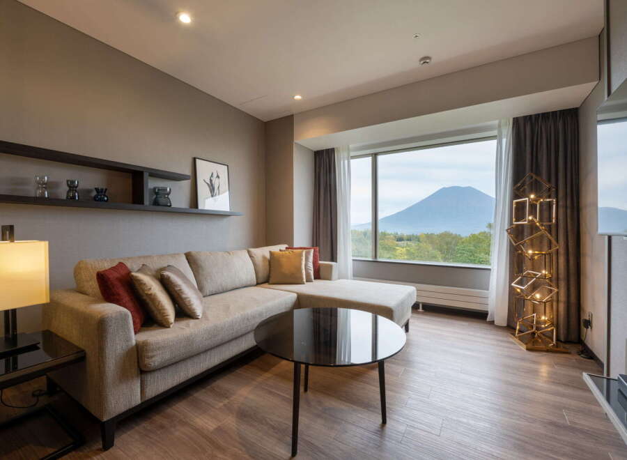 This inviting living room boasts a comfortable sectional sofa, perfect for relaxing and enjoying the stunning mountain views through the expansive window.
