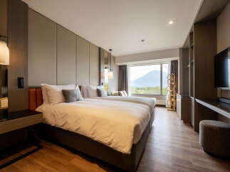 Indulge in the comfort of this hotel room featuring twin beds, a large window with scenic mountain views, and modern decor.