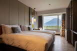 This hotel room offers a serene retreat with its plush double beds, stylish lighting, and a stunning view of the mountain.