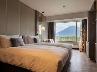 This hotel room offers a serene retreat with its plush double beds, stylish lighting, and a stunning view of the mountain.