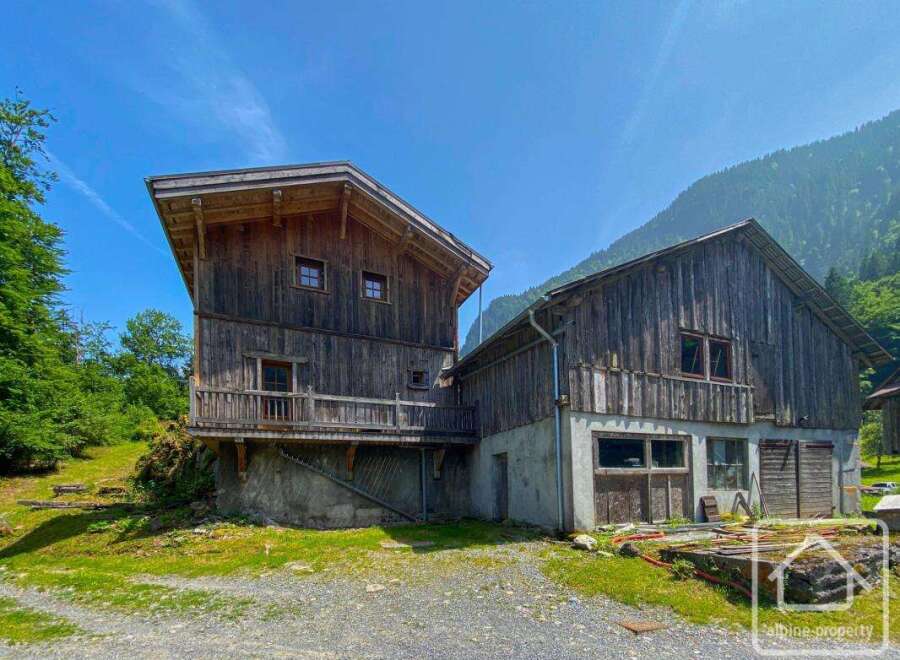 Discover a unique alpine property featuring a rustic wooden chalet nestled in a picturesque mountain setting.
