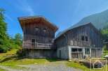 Discover a unique alpine property featuring a rustic wooden chalet nestled in a picturesque mountain setting.