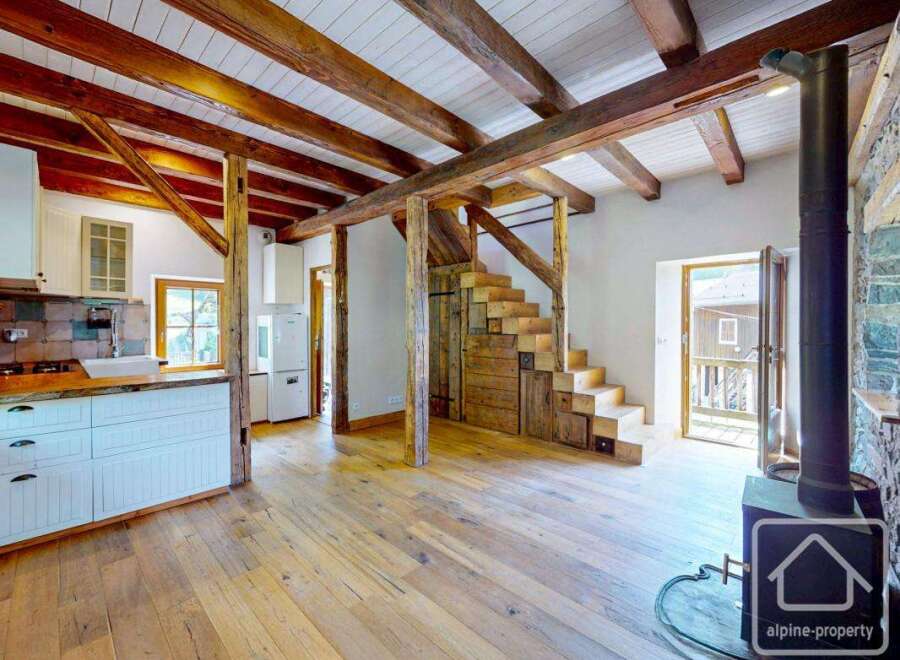 Discover a unique alpine property featuring exposed wooden beams, a cozy fireplace, and custom wooden stairs.