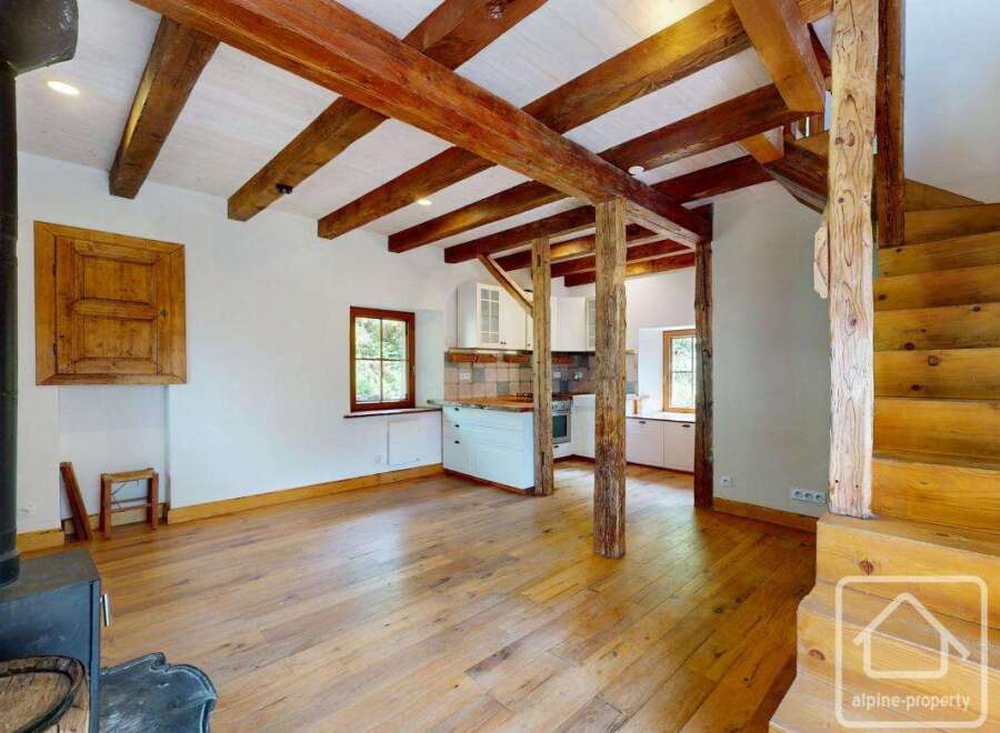 This property showcases an open floor plan with rustic wooden beams and hardwood floors.
