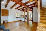 This property showcases an open floor plan with rustic wooden beams and hardwood floors.