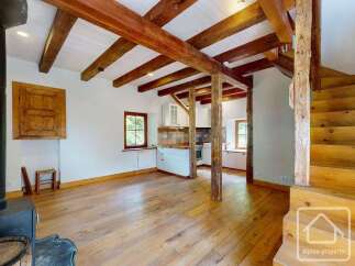 This property showcases an open floor plan with rustic wooden beams and hardwood floors.