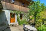 Charming chalet exterior featuring a stone foundation adorned with climbing vines and red roses, complemented by wooden cladding.