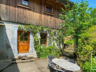 Charming chalet exterior featuring a stone foundation adorned with climbing vines and red roses, complemented by wooden cladding.