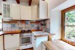 This charming kitchen features white cabinetry, a wooden countertop, and a rustic tiled backsplash.