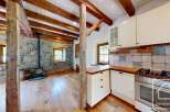 This property features a rustic interior with exposed wooden beams, a stone wall, and hardwood flooring.
