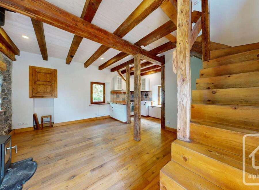This charming property features a rustic interior with exposed wooden beams, a stone fireplace, and hardwood floors.