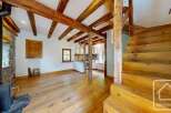 This charming property features a rustic interior with exposed wooden beams, a stone fireplace, and hardwood floors.
