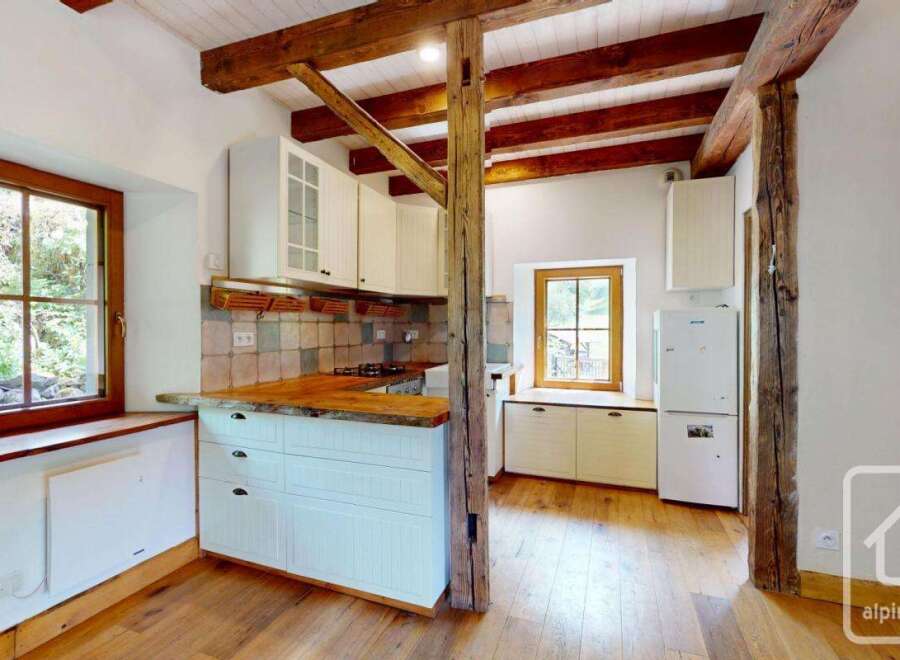 Step inside this charming kitchen, featuring rustic wooden beams and pristine white cabinetry.