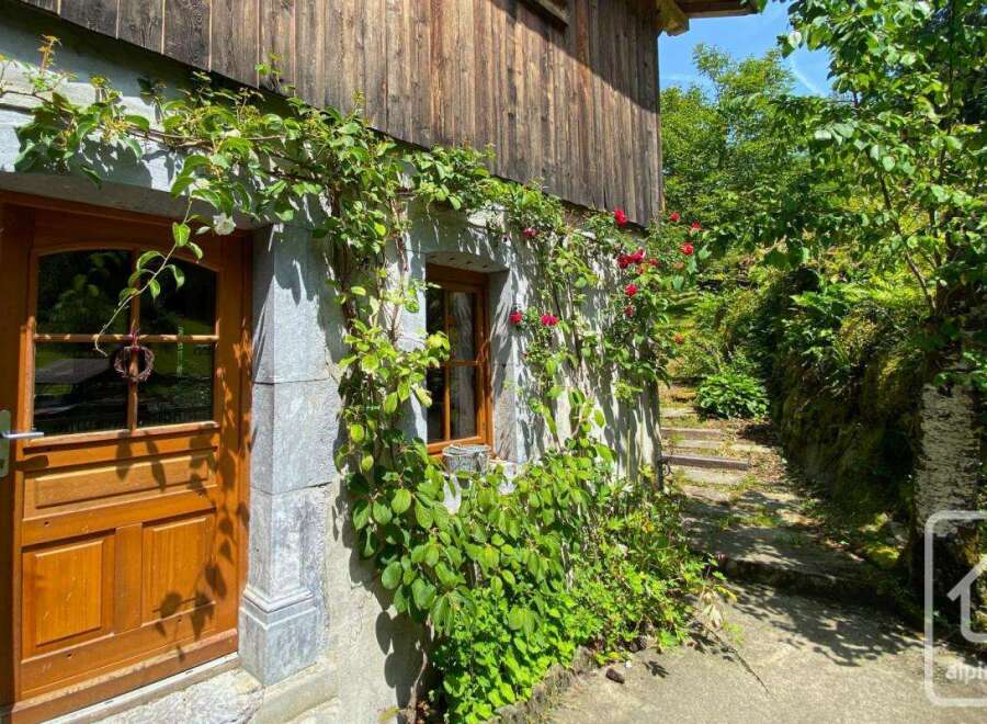 This charming property features a rustic wooden exterior adorned with lush greenery and vibrant red roses.