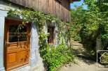 This charming property features a rustic wooden exterior adorned with lush greenery and vibrant red roses.