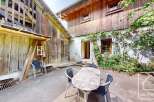 This charming property showcases traditional architecture with a rustic wooden facade complemented by lush greenery.