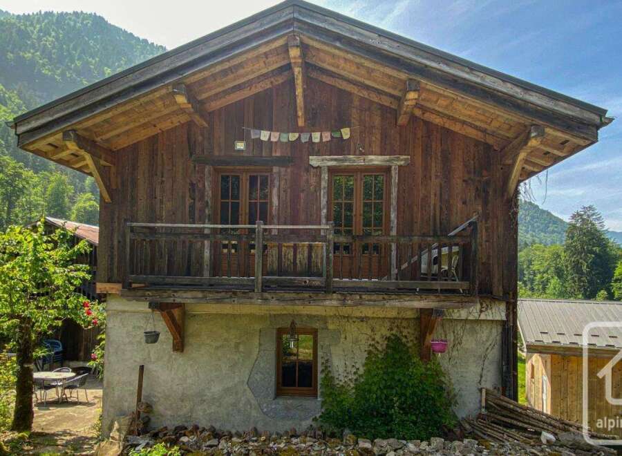 Discover a charming alpine property with rustic wooden architecture, set against a backdrop of lush green mountains.