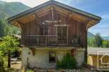 Discover a charming alpine property with rustic wooden architecture, set against a backdrop of lush green mountains.