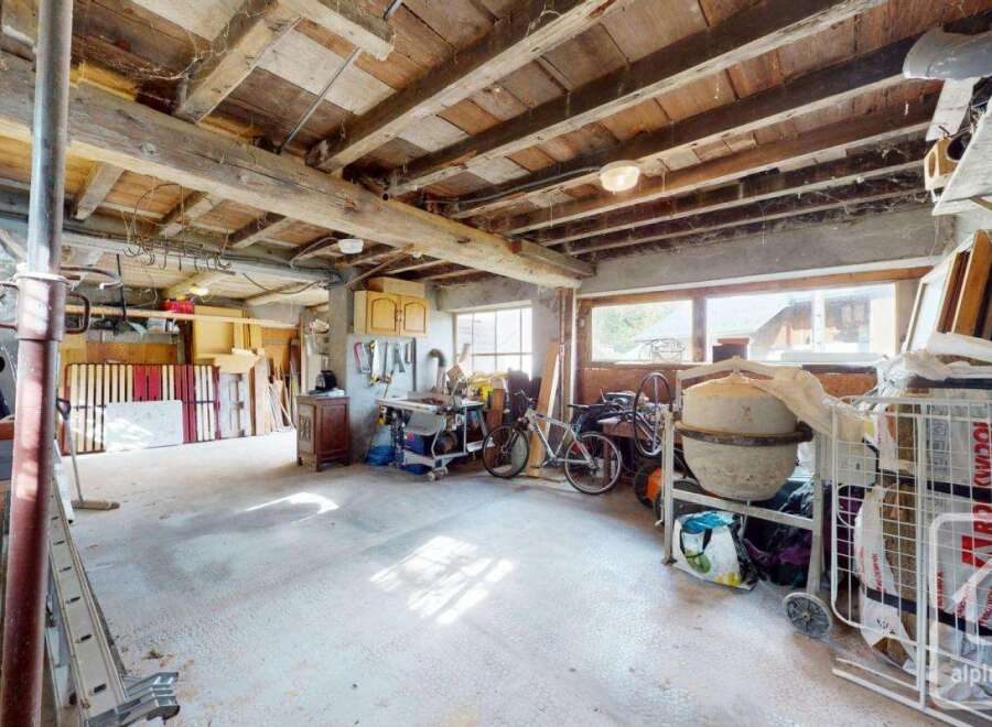 This is a spacious garage with exposed wooden beams, offering a rustic charm and ample storage.