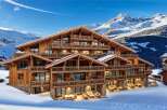 A luxurious chalet nestled in a snowy mountain landscape, featuring multiple balconies and expansive windows.