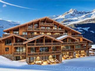 A luxurious chalet nestled in a snowy mountain landscape, featuring multiple balconies and expansive windows.