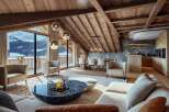 This luxurious chalet boasts stunning mountain views visible through large windows, seamlessly blending indoor comfort with the beauty of nature.