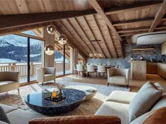 This luxurious chalet boasts stunning mountain views visible through large windows, seamlessly blending indoor comfort with the beauty of nature.