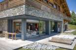 This luxury chalet boasts a seamless blend of rustic charm and modern design, featuring stone and wood exterior, expansive glass windows, and a tranquil indoor pool area.