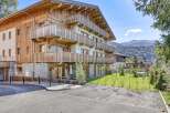 Discover this stunning chalet-style apartment building with wooden balconies, offering breathtaking mountain views.