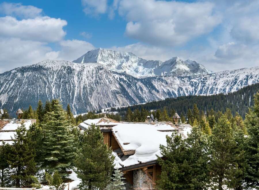 Experience luxury living in this stunning mountain chalet, complete with snow-covered rooftops and breathtaking views.