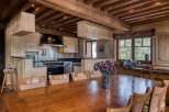 This inviting kitchen and dining area boasts rustic charm with exposed wooden beams and cabinetry, perfect for a cozy mountain retreat.