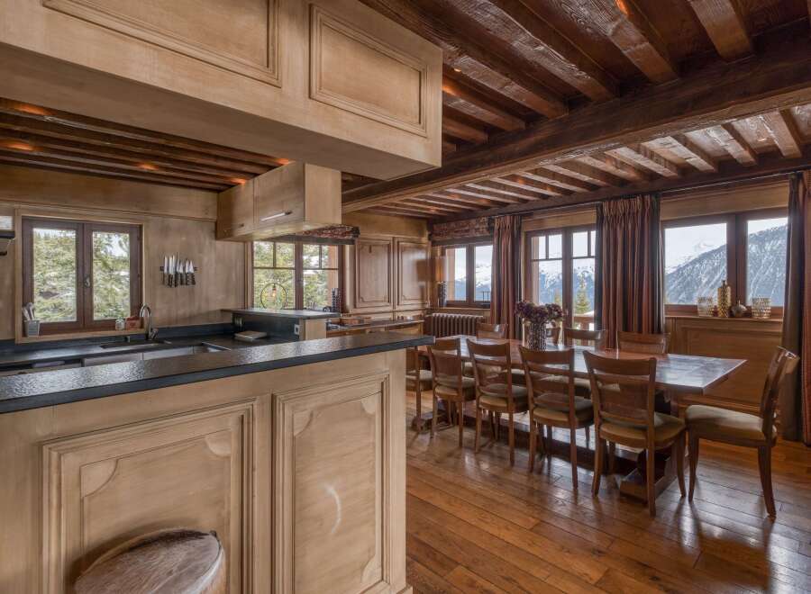 This expansive kitchen and dining area is perfect for entertaining, featuring sleek black countertops and a large wooden dining table.